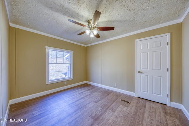 spare room with a textured ceiling, light hardwood / wood-style flooring, ornamental molding, and ceiling fan