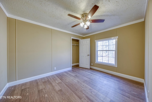 unfurnished bedroom featuring crown molding, a closet, ceiling fan, and light hardwood / wood-style flooring