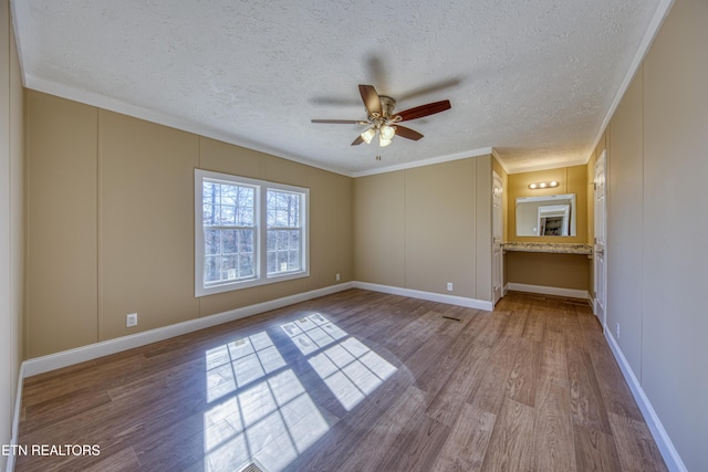 unfurnished room with ceiling fan, wood-type flooring, ornamental molding, and a textured ceiling