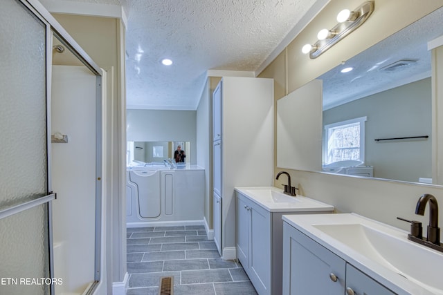 bathroom with vanity, a textured ceiling, and independent washer and dryer