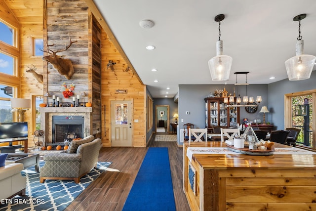 kitchen with a stone fireplace, butcher block counters, decorative light fixtures, wooden walls, and dark hardwood / wood-style flooring