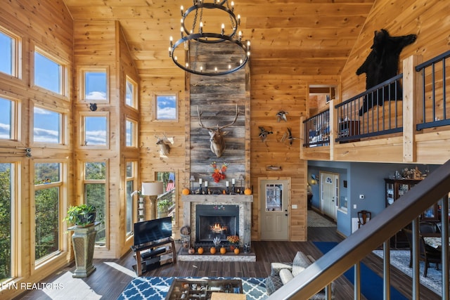 living room featuring dark wood-type flooring, a notable chandelier, high vaulted ceiling, and wood walls