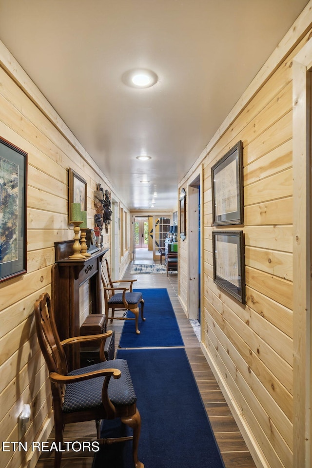 hallway with dark hardwood / wood-style floors and wood walls