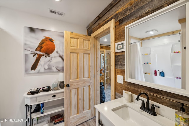 bathroom with vanity, curtained shower, and wood walls