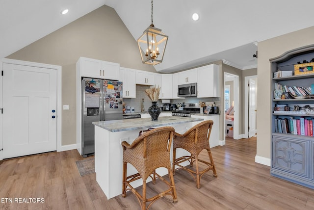309 W Cleveland Ave, Monterey, TN 38574 - kitchen with a kitchen bar, light stone counters, decorative light fixtures, appliances with stainless steel finishes, and white cabinets