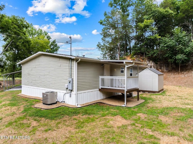 rear view of property with a storage unit, a yard, and central AC unit