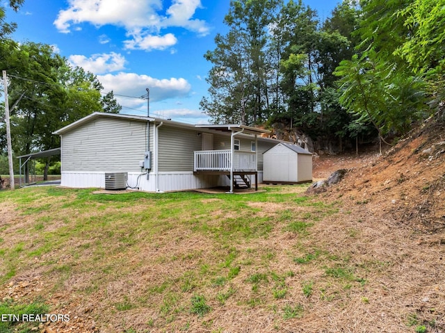 rear view of house with a carport, a yard, central AC unit, and a storage shed