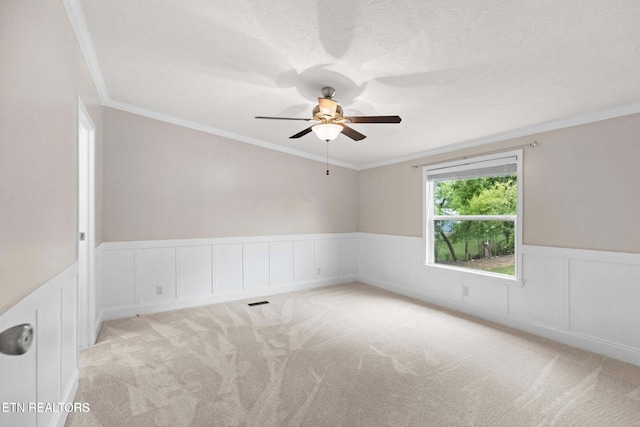 carpeted empty room with crown molding, ceiling fan, and a textured ceiling