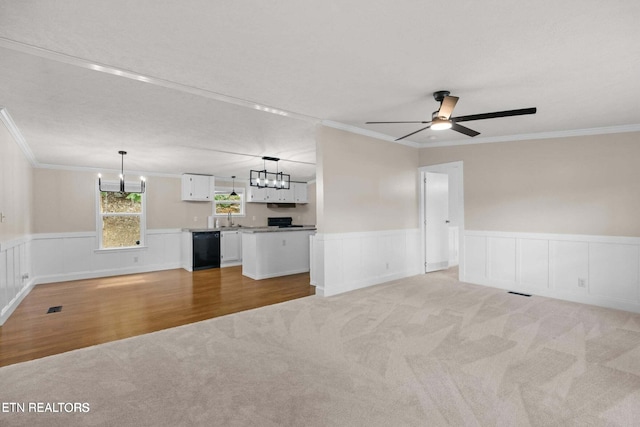 unfurnished living room featuring crown molding, ceiling fan with notable chandelier, sink, and light carpet