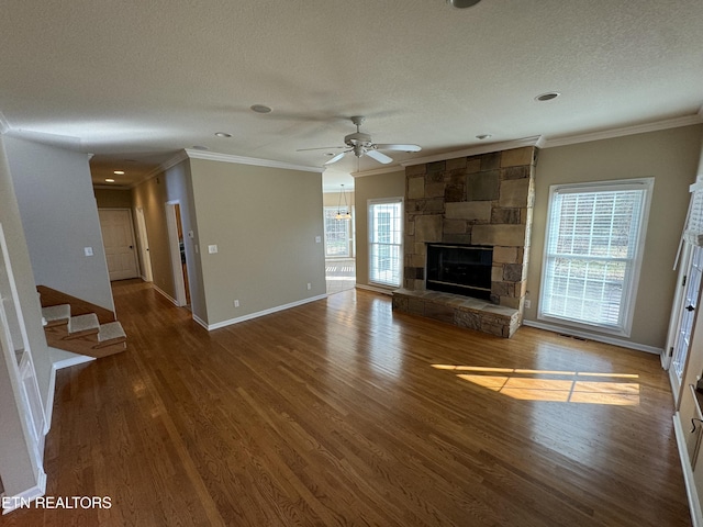 unfurnished living room with crown molding, a textured ceiling, ceiling fan, a fireplace, and hardwood / wood-style floors