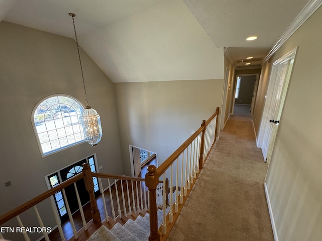 hallway with a chandelier, light carpet, and high vaulted ceiling