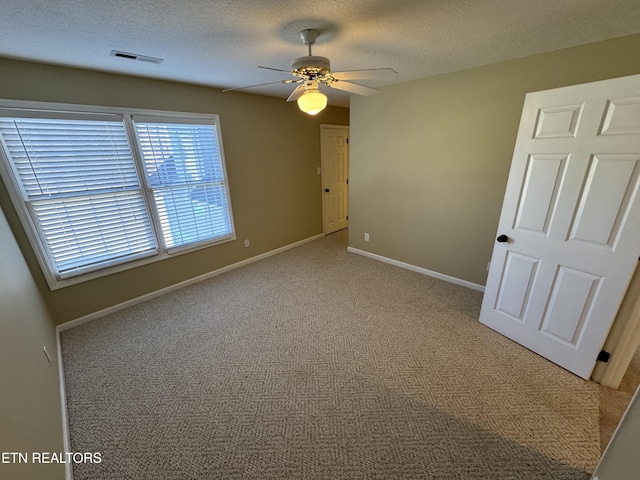 empty room featuring ceiling fan, carpet flooring, and a textured ceiling