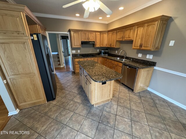 kitchen featuring sink, crown molding, black appliances, a kitchen island, and dark stone counters