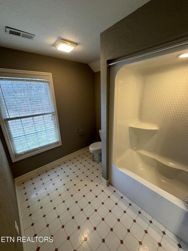 bathroom with vaulted ceiling, a textured ceiling, and toilet