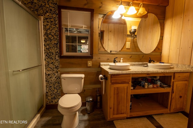 bathroom featuring an enclosed shower, vanity, wooden walls, and toilet