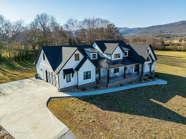 view of front of property with a mountain view, a garage, a front lawn, and a porch