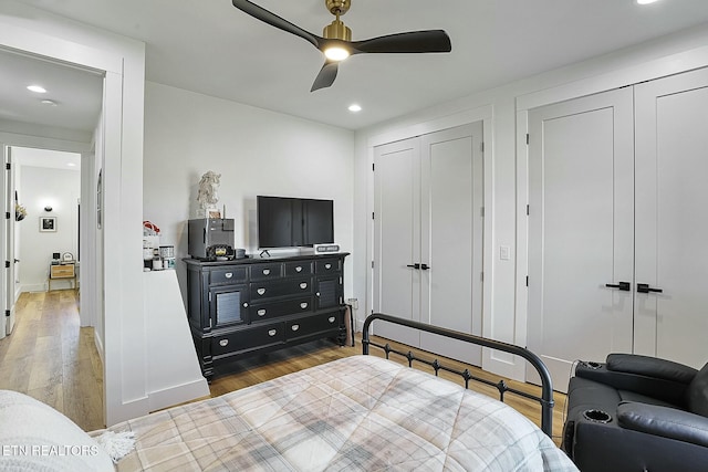 bedroom with dark hardwood / wood-style floors, two closets, and ceiling fan