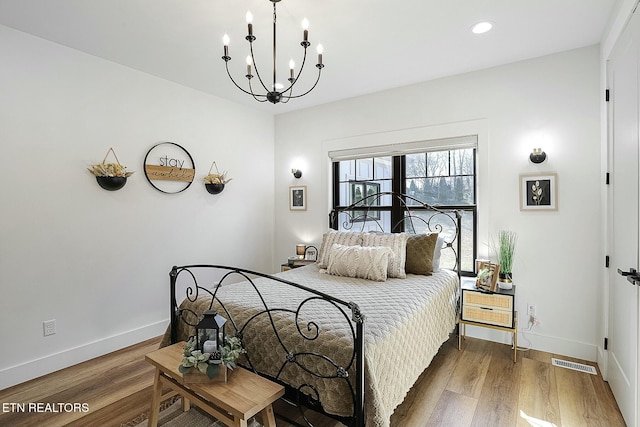 bedroom featuring wood-type flooring and an inviting chandelier