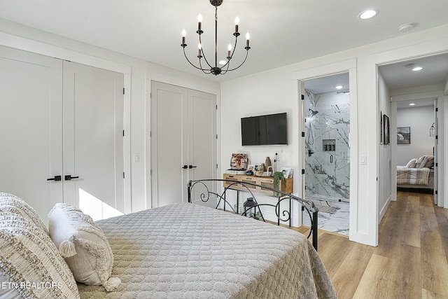 bedroom featuring connected bathroom, a notable chandelier, light hardwood / wood-style flooring, and a closet