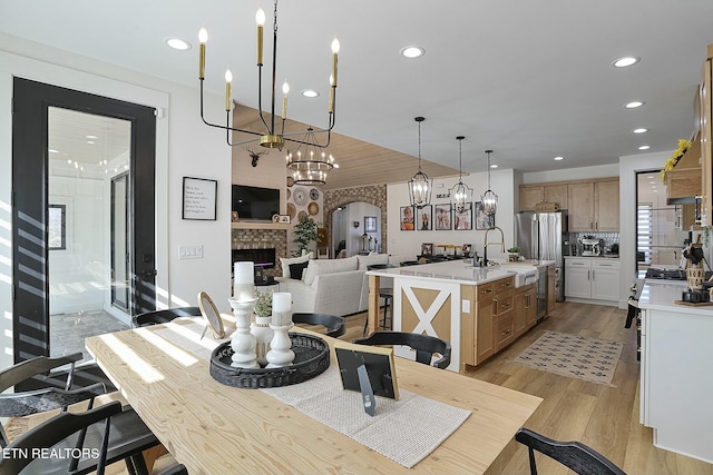 dining space with an inviting chandelier, sink, and light hardwood / wood-style flooring