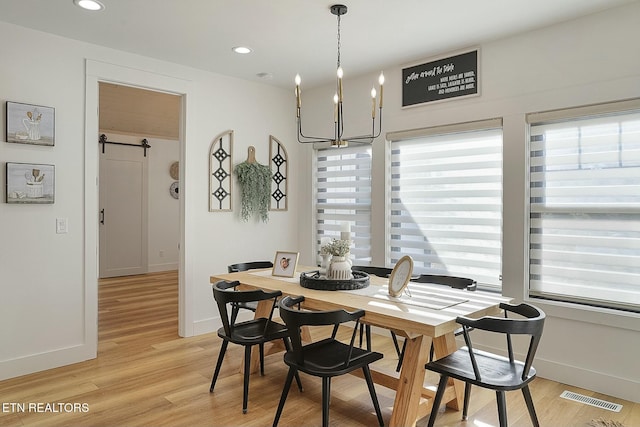 dining space with a wealth of natural light, light hardwood / wood-style flooring, and a barn door