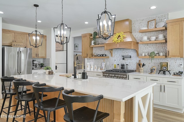 kitchen with premium range hood, a center island with sink, white cabinets, and range