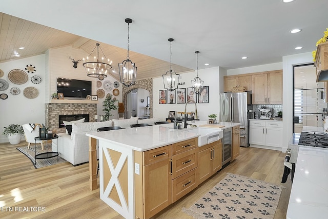 kitchen featuring light stone counters, sink, decorative light fixtures, and an island with sink