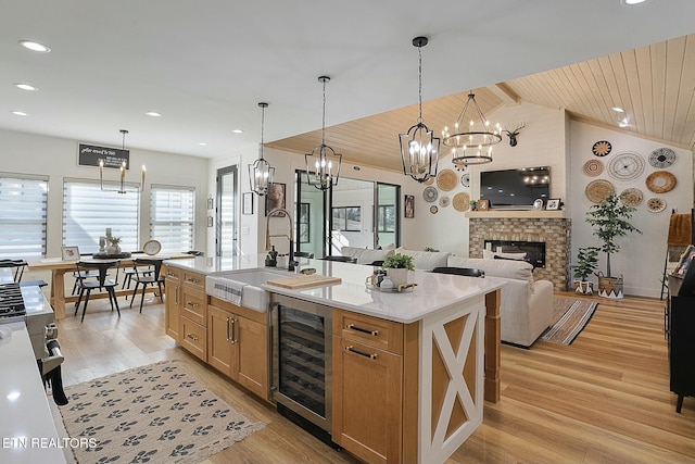 kitchen with sink, a center island with sink, beverage cooler, and wood ceiling