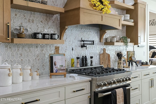 kitchen featuring backsplash, stainless steel range with gas cooktop, light stone countertops, and white cabinets