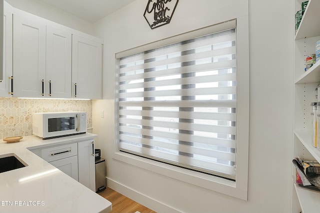 kitchen featuring white cabinetry, light wood-type flooring, and a wealth of natural light