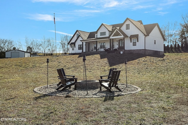 view of front of property with a porch, a front lawn, and an outdoor fire pit