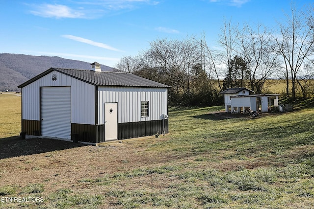 view of outbuilding with a mountain view, a garage, and a lawn