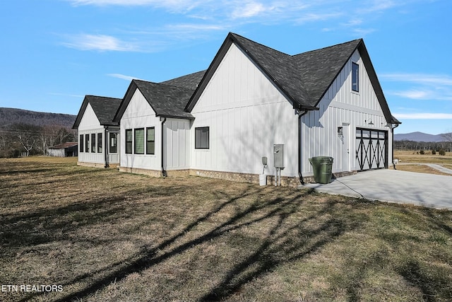 view of side of property with a yard, a mountain view, and a garage