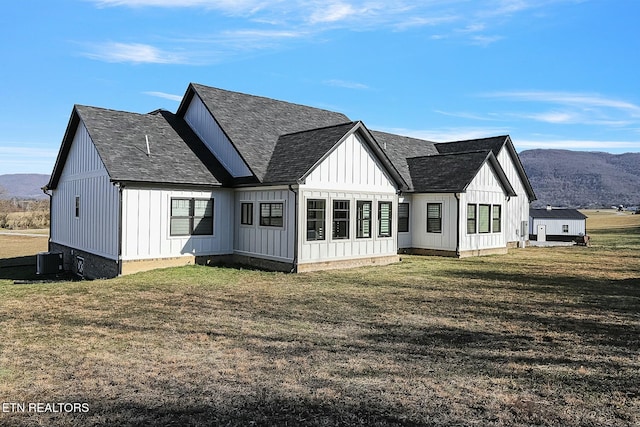 rear view of property featuring a mountain view, central AC, and a lawn