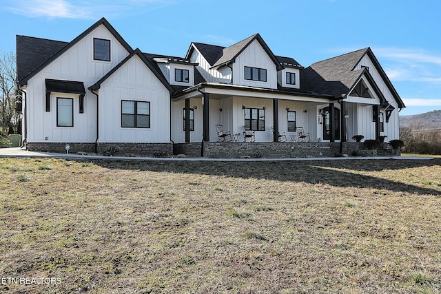 modern inspired farmhouse featuring covered porch and a front lawn