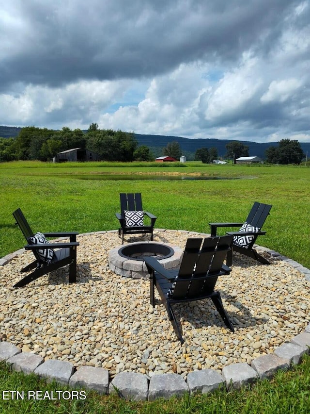 surrounding community with a yard, a fire pit, and a rural view