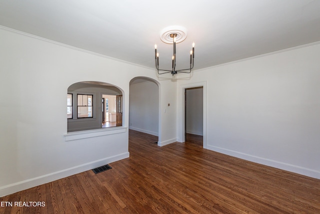 unfurnished room with a chandelier, dark wood-type flooring, visible vents, baseboards, and ornamental molding