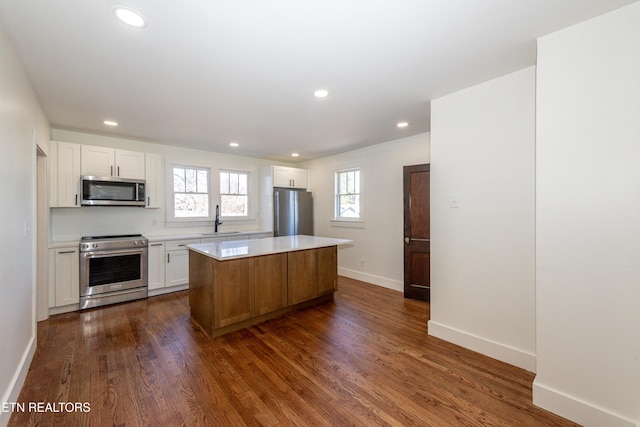 kitchen featuring white cabinets, a kitchen island, stainless steel appliances, and light countertops