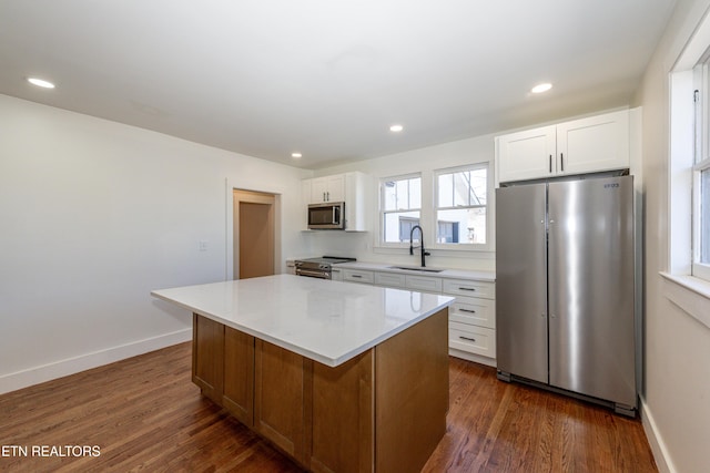 kitchen featuring appliances with stainless steel finishes, a sink, white cabinets, and a center island