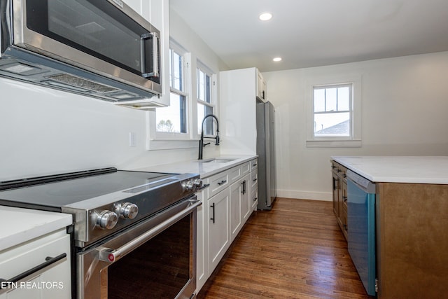 kitchen with appliances with stainless steel finishes, light countertops, white cabinets, and plenty of natural light