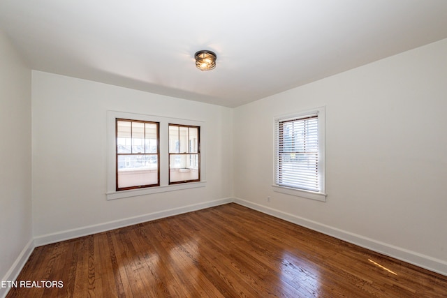 spare room featuring baseboards and dark wood-type flooring