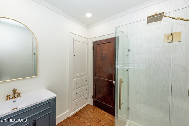 full bath with crown molding, vanity, wood finished floors, tiled shower, and baseboards