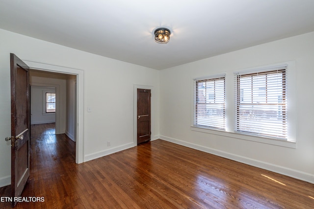 unfurnished room featuring dark wood-type flooring and baseboards