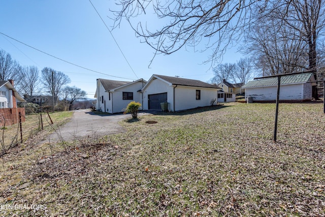 view of side of home featuring aphalt driveway, fence, and an attached garage