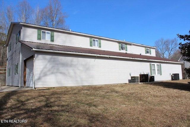 rear view of property with a garage, a yard, and central air condition unit