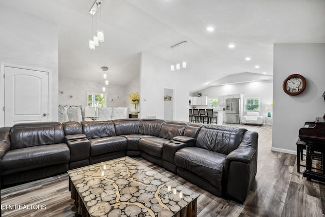 living room with hardwood / wood-style flooring, an inviting chandelier, and high vaulted ceiling