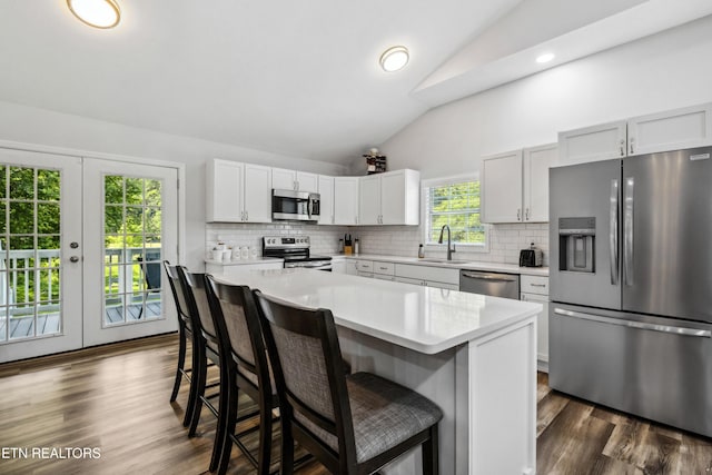 kitchen featuring a kitchen island, appliances with stainless steel finishes, white cabinetry, lofted ceiling, and sink