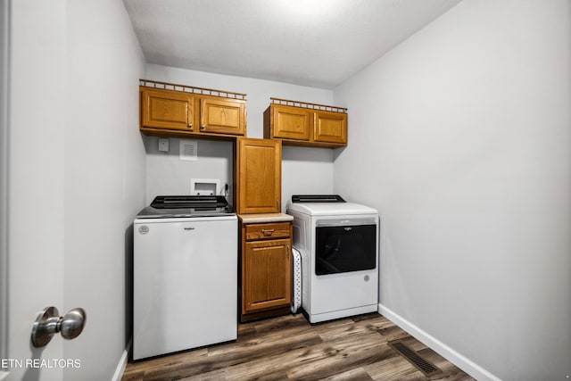 laundry room featuring dark hardwood / wood-style flooring, separate washer and dryer, and cabinets