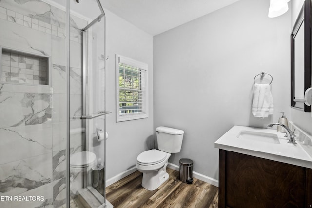 bathroom featuring vanity, toilet, a shower with shower door, and wood-type flooring