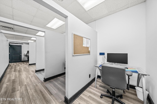 office area featuring a paneled ceiling and light hardwood / wood-style flooring